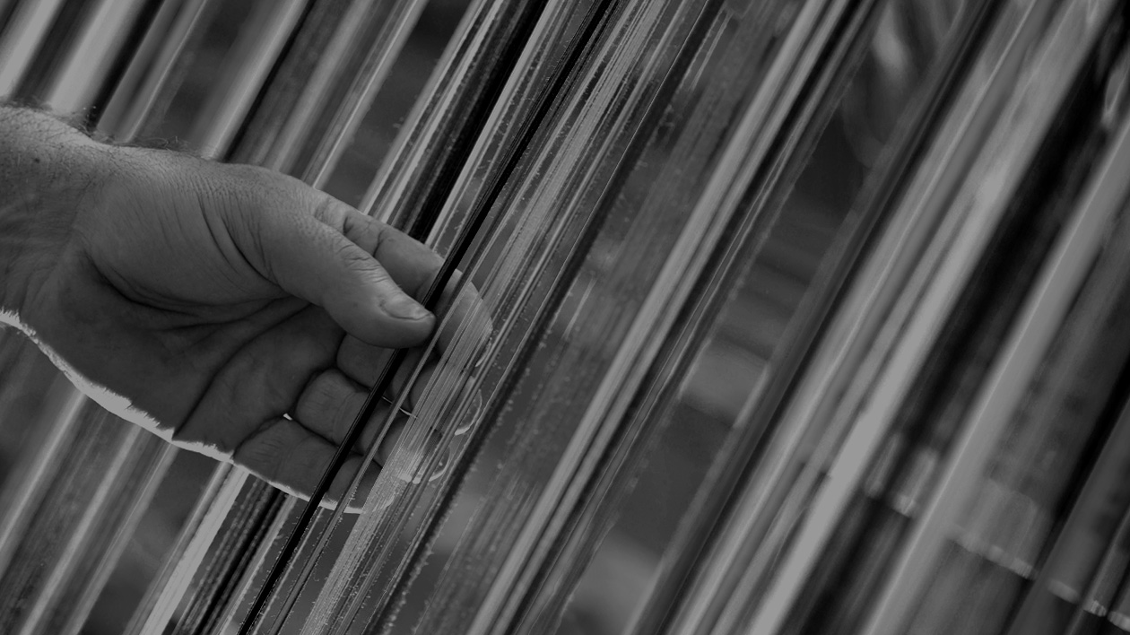 Black and white photo of a hand grasping strands of Filium's eco-friendly textiles