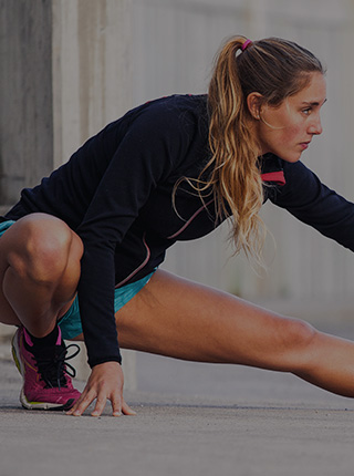 Woman athlete with pink shoes stretches with a serious expression, wearing Filium-activated sports apparel [Mobile crop]