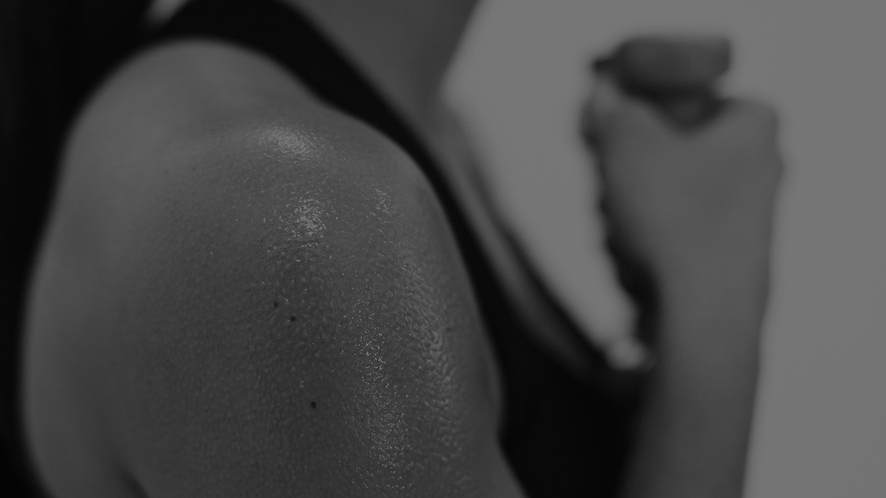 Black and white photo of a bicep of a woman athlete covered in sweat during a workout